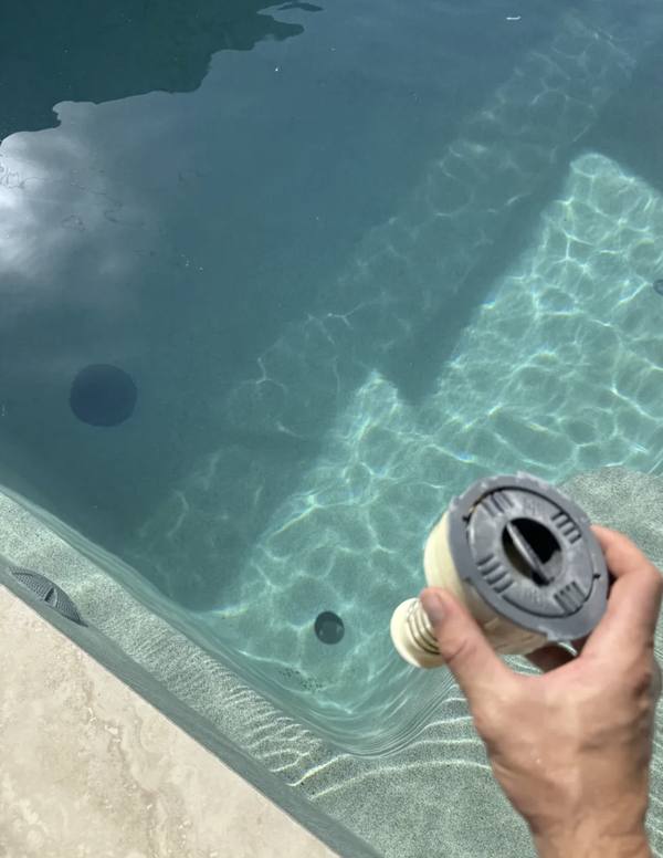 Pop-up head held next to pool with in-floor ports visible