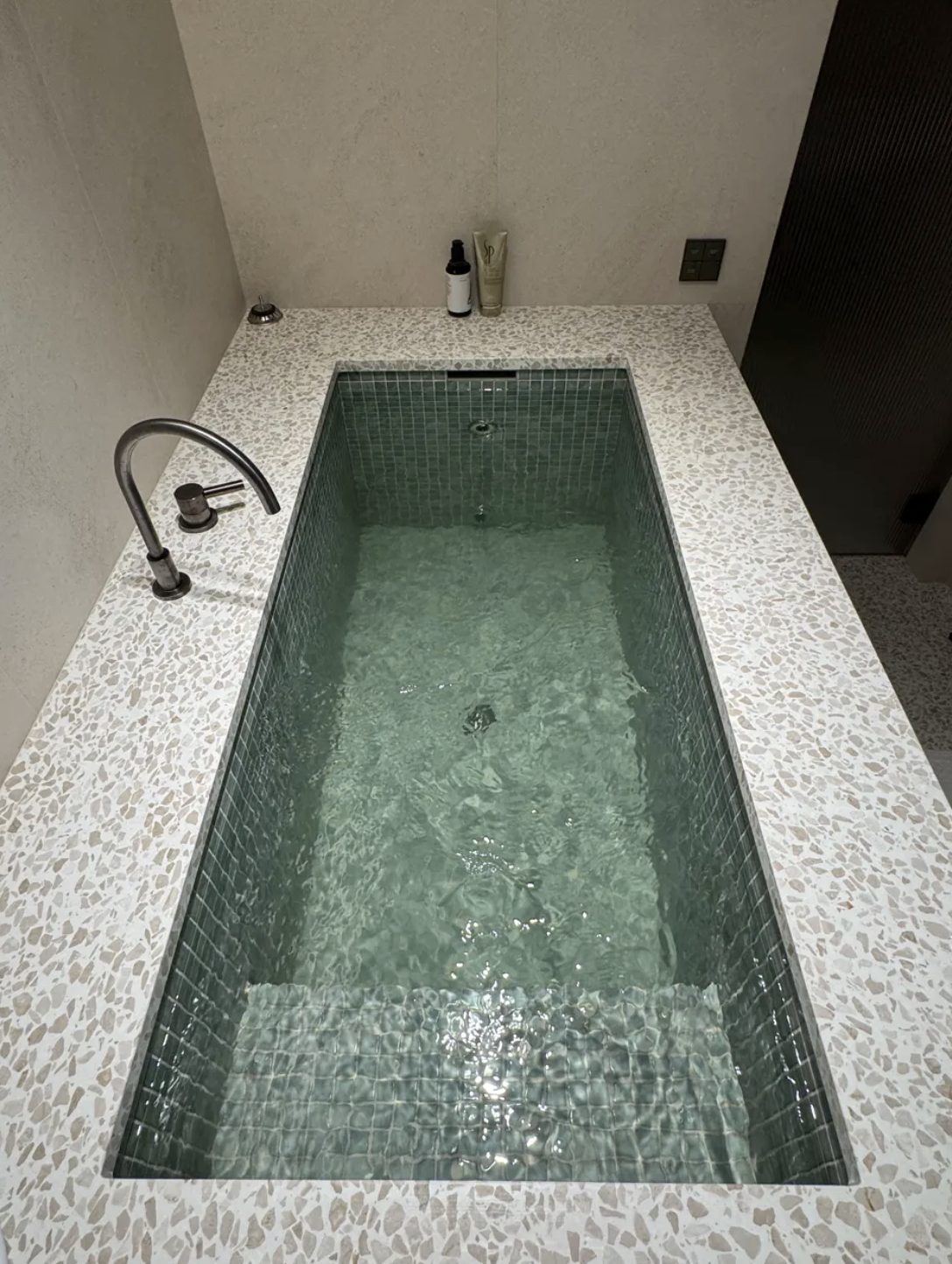 Green mosaic tiled cold plunge with terrazzo surround