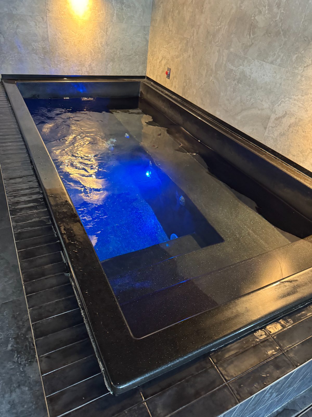 Sunken black-tiled plunge pool with underwater lighting
